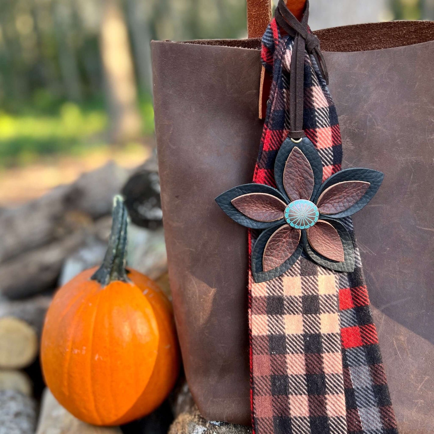 black and brown genuine leather flower bag charm shown on tote with flannel scarf