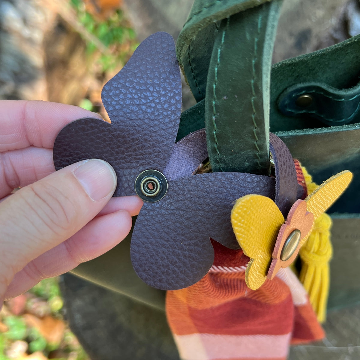 leather butterfly snap on bag charm in burgundy, yellow and orange shown with plaid scarf and yellow tassel