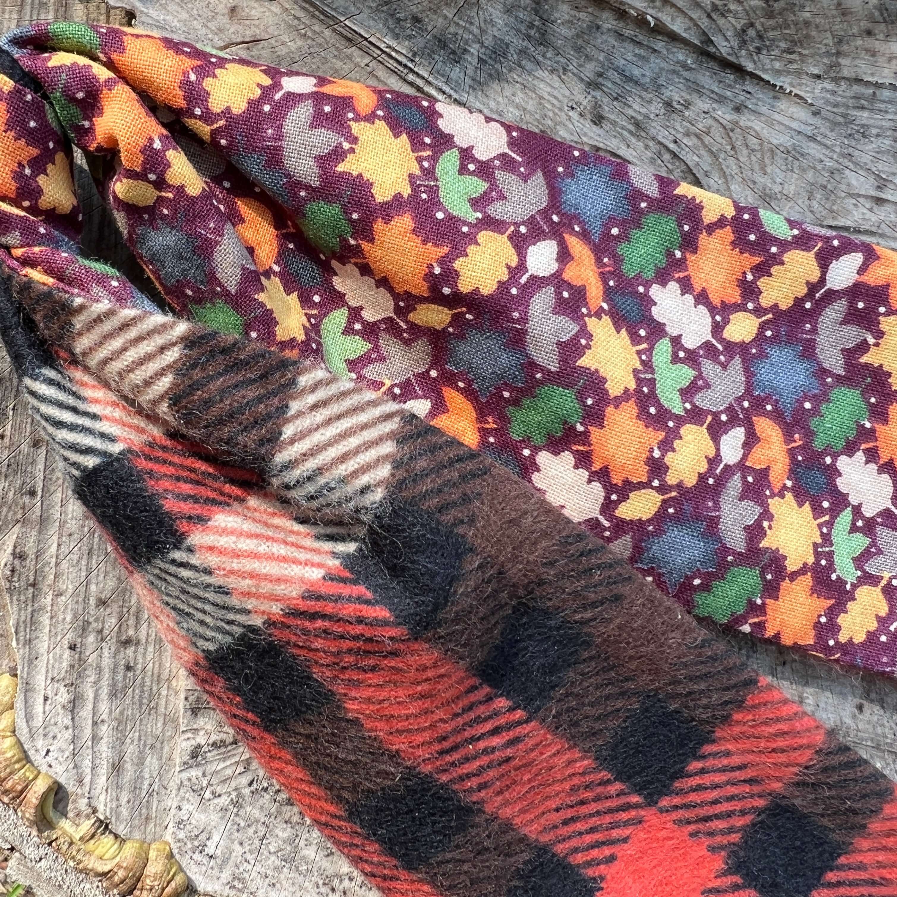 Two fabric swatches with autumn leaf pattern and plaid design on a wooden surface.
