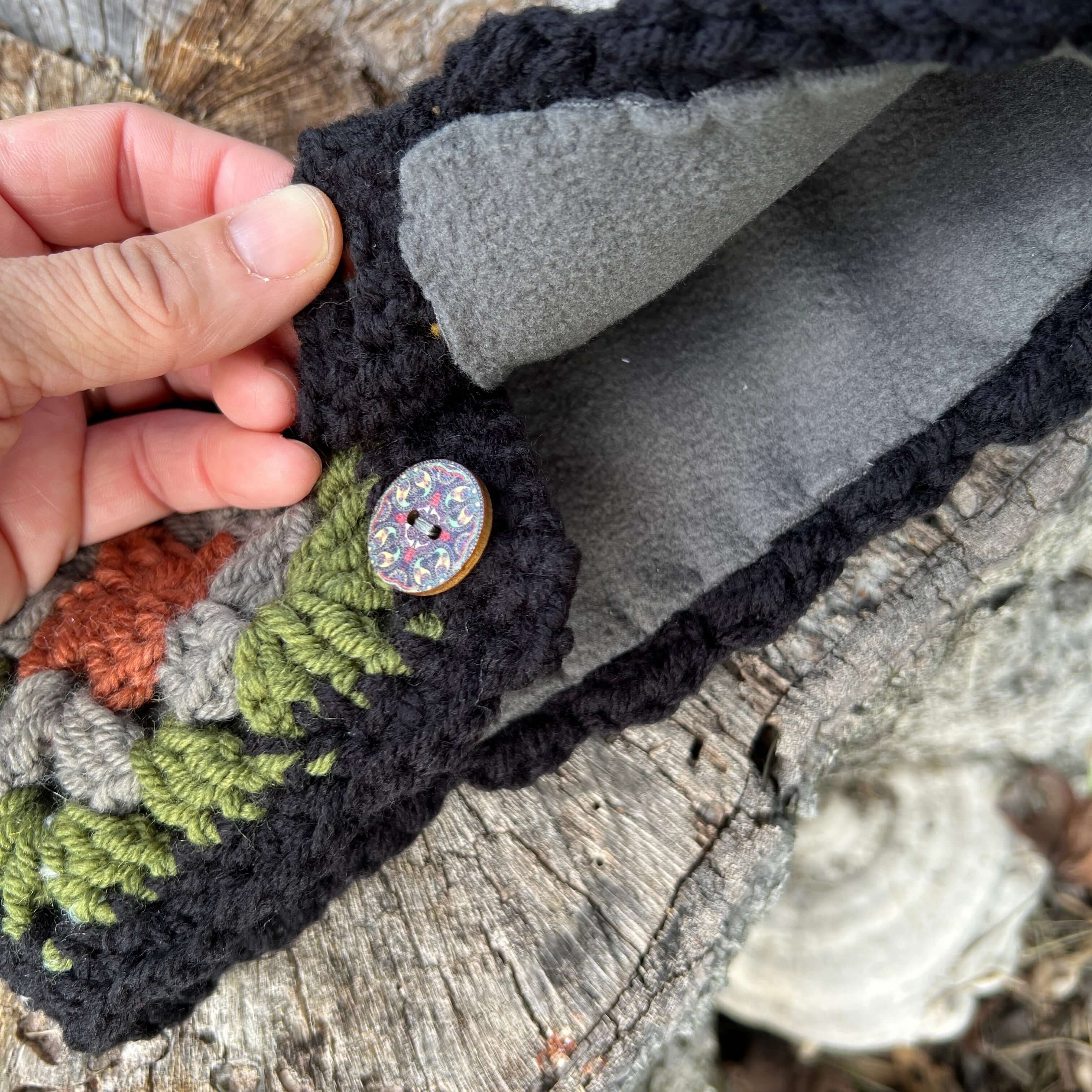 Handmade crochet item with a button on a wooden surface