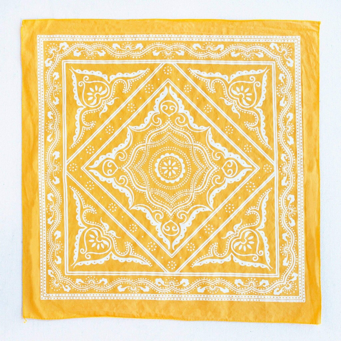 Yellow bandana with white intricate patterns on a white background