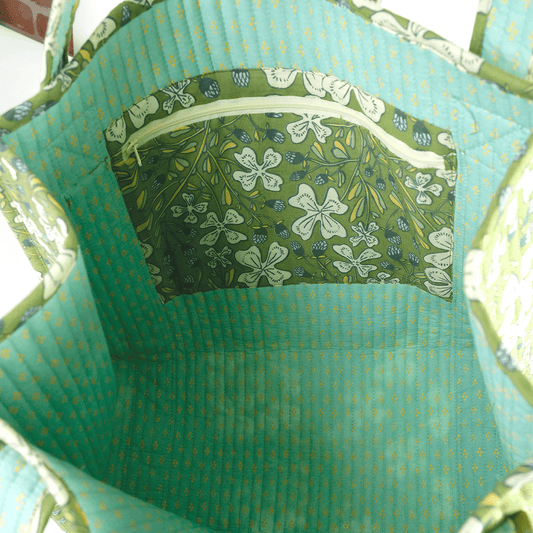 Close-up of a green fabric bag with floral patterned pocket.