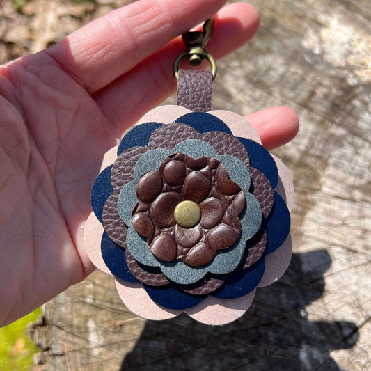 leather flower key chain in blue and brown on a wooden surface