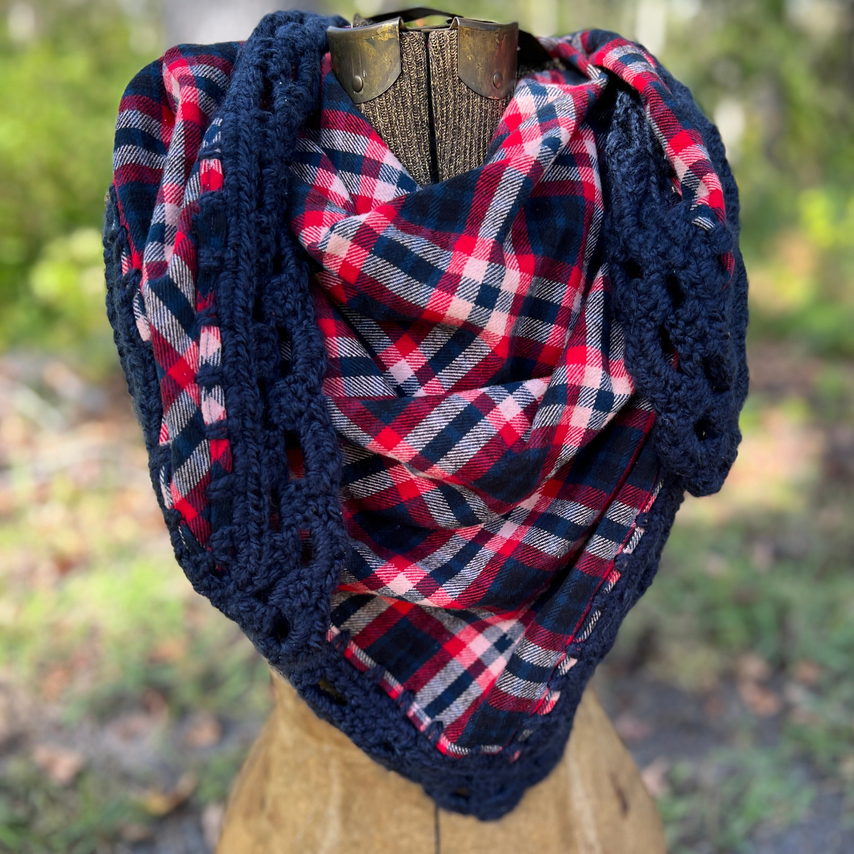 Plaid shawl with crochet border on a mannequin against a blurred natural background