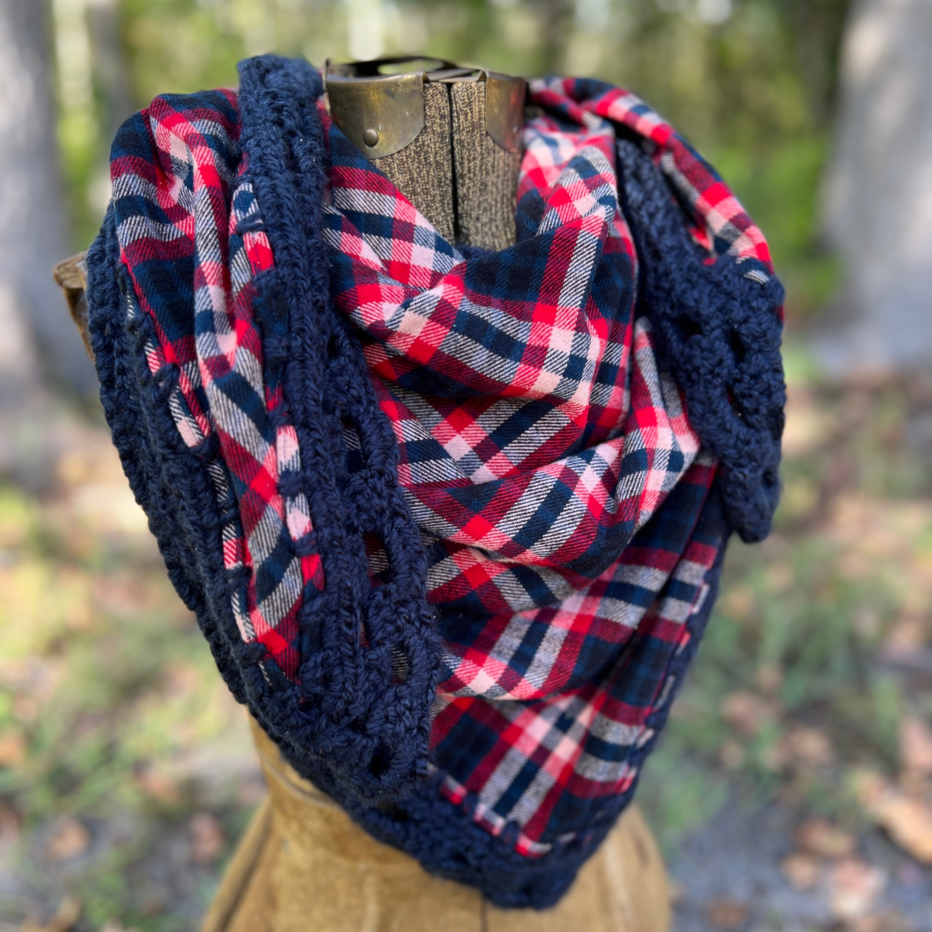 Plaid scarf with crochet border on a wooden mannequin against a blurred natural background