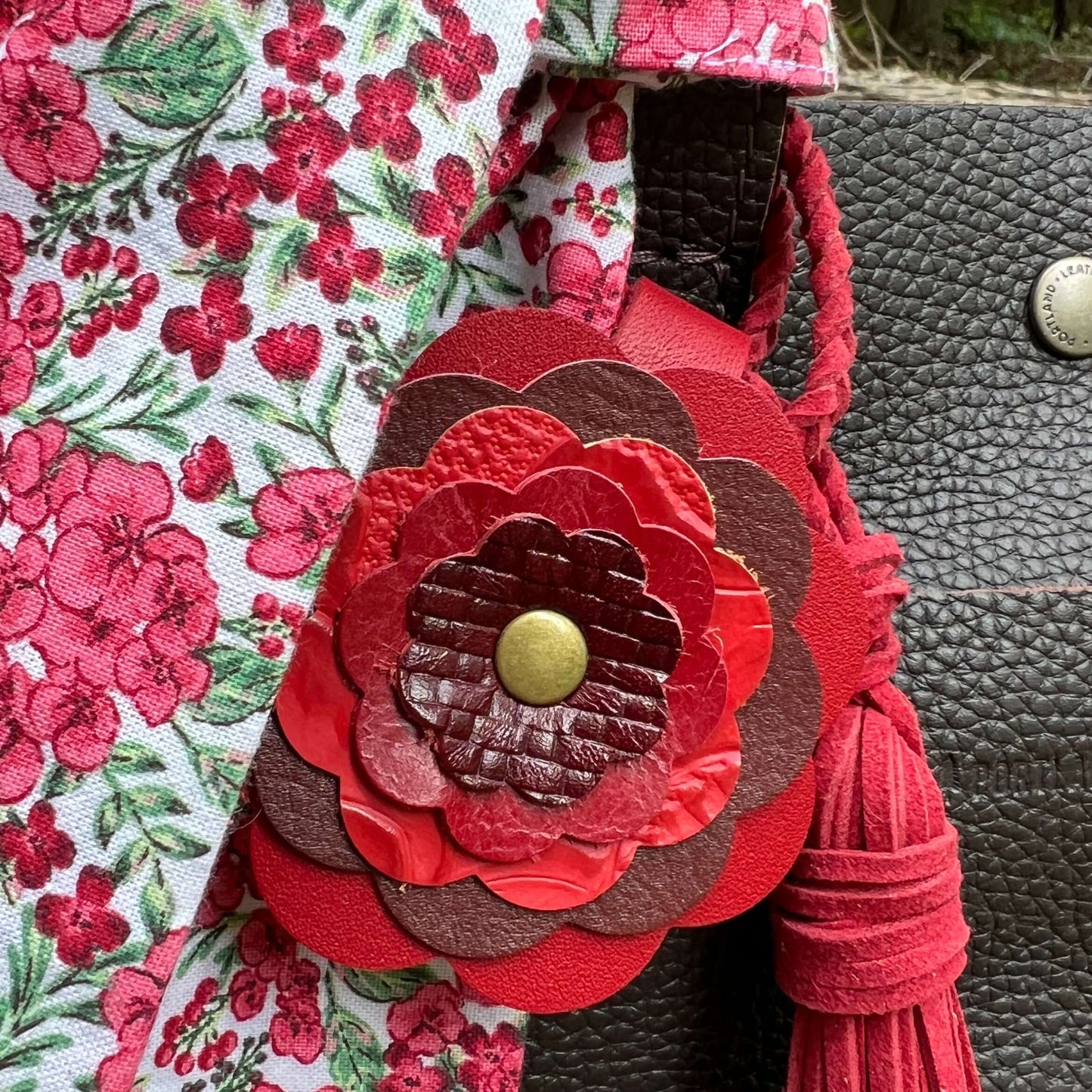 Close-up of a floral-patterned bag with a red leather flower detail.