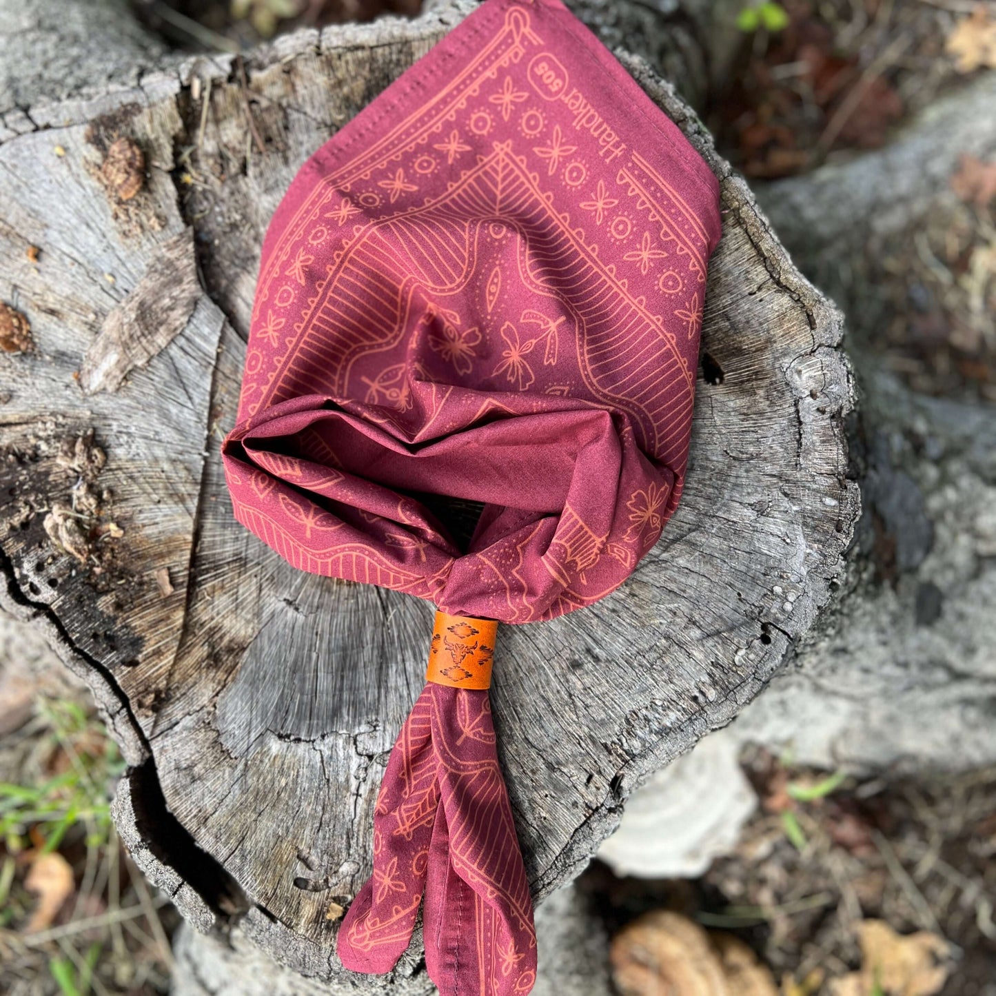 Red patterned headscarf tied around a stick on a wooden log