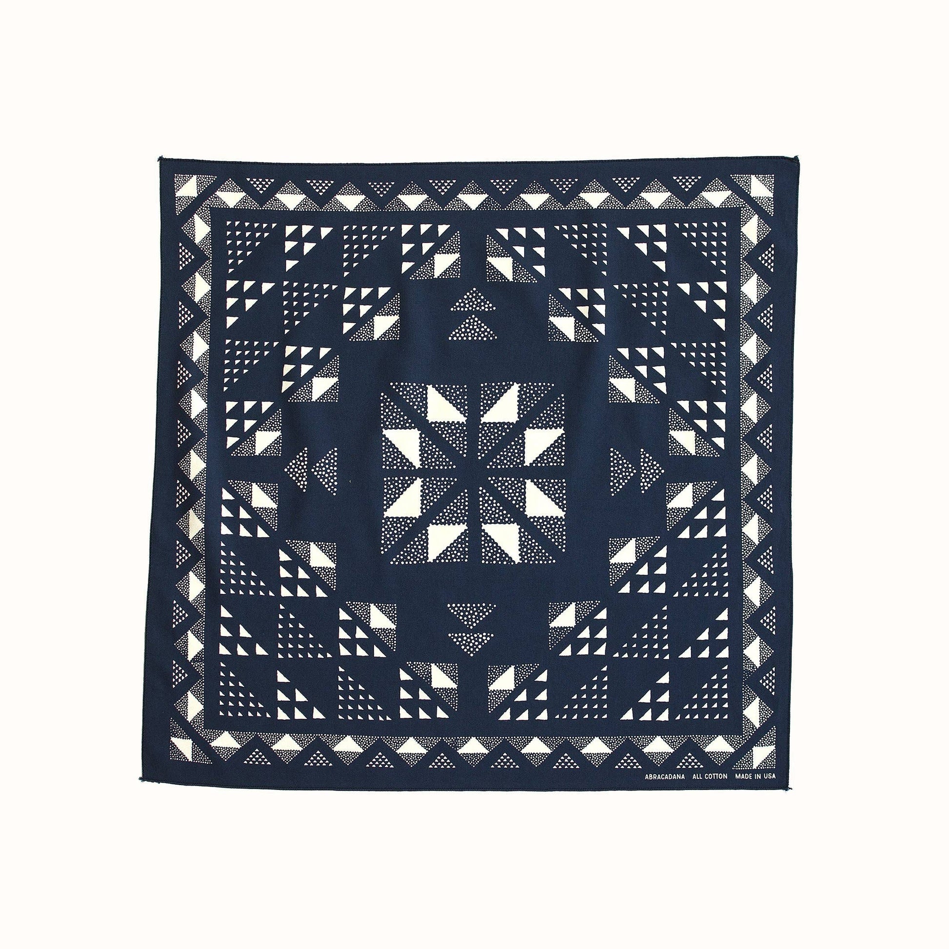 A square navy blue bandana featuring a white geometric quilted pattern, displayed flat against a solid off-white background.