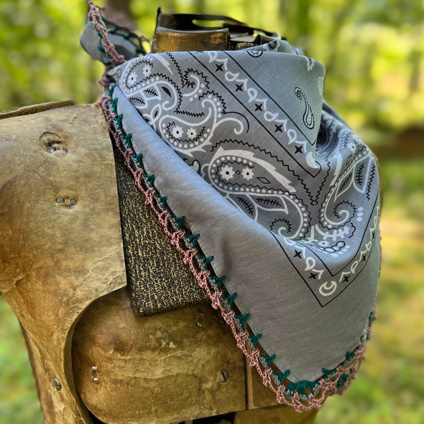 Gray bandana with white paisley pattern draped over a wooden object outdoors