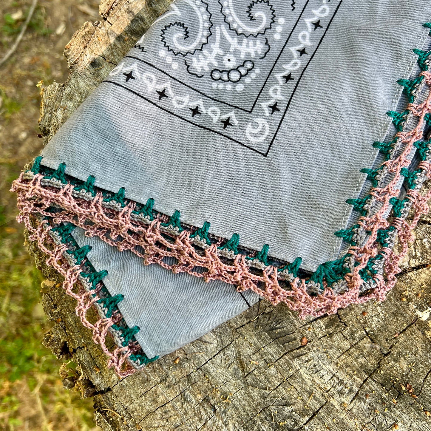 Gray bandana with black paisley design on a wooden surface