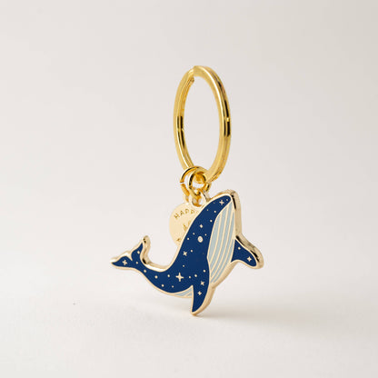 Gold and blue whale-shaped pendant on a light gray background