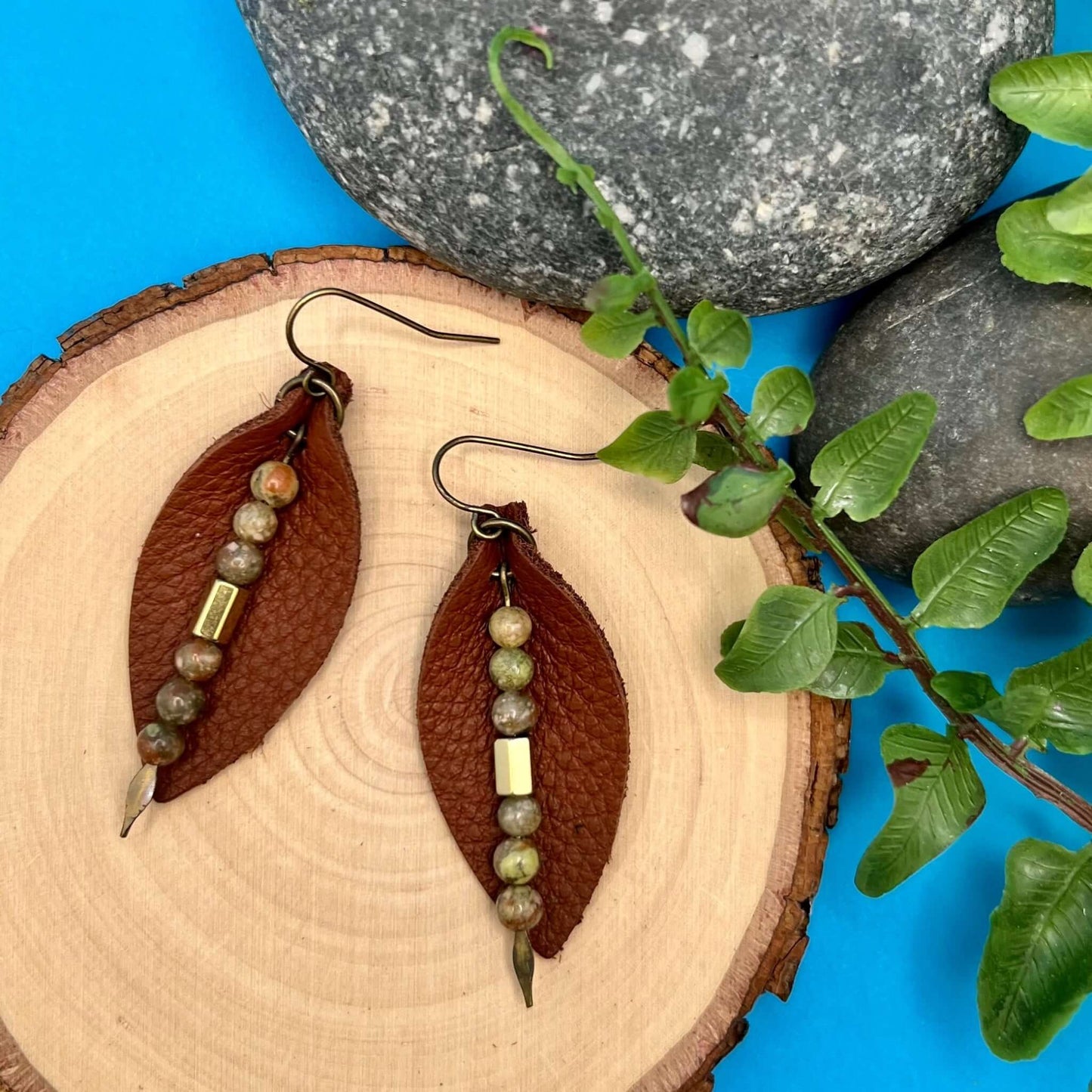 Leather Petal Earrings - Warm Brown with Autumn JasperAdd a little boho flair to your day with genuine leather earrings. Warm brown leather petal is accented with genuine Jasper and bronze glass bead on antique gold arrowhead pin. Lightweight earrings are