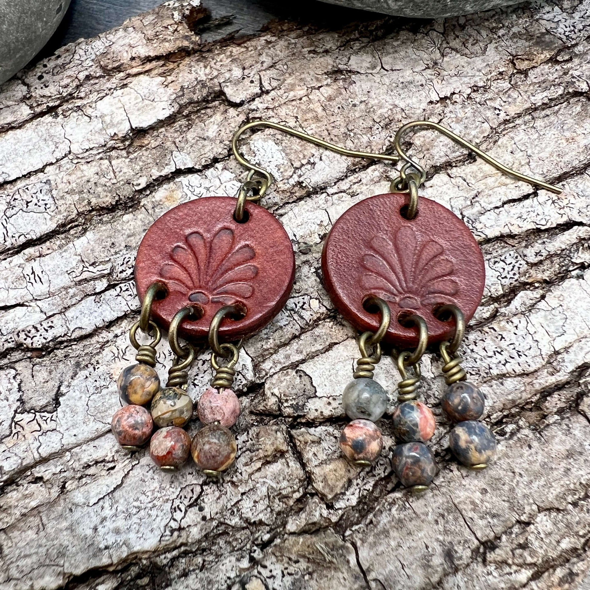 Leather Coin Earrings with Natural Stone DanglesLeather coin earrings are cut from genuine veg tanned leather, stamped and dyed in a antiqued saddle tan or dark brown. Accented with a trio of natural stone dangles these rustic bohemian style compliments a