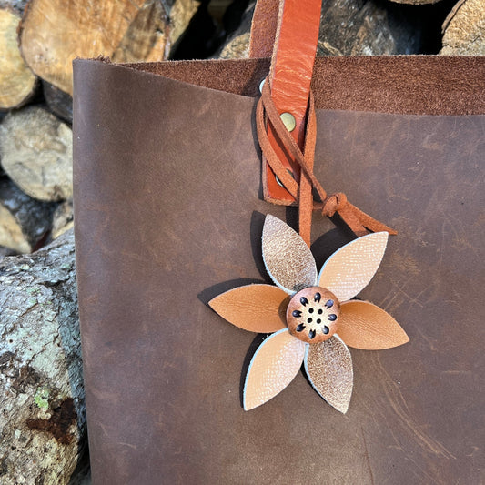 brown and beige genuine leather flower bag charm shown on brown leather tote bag