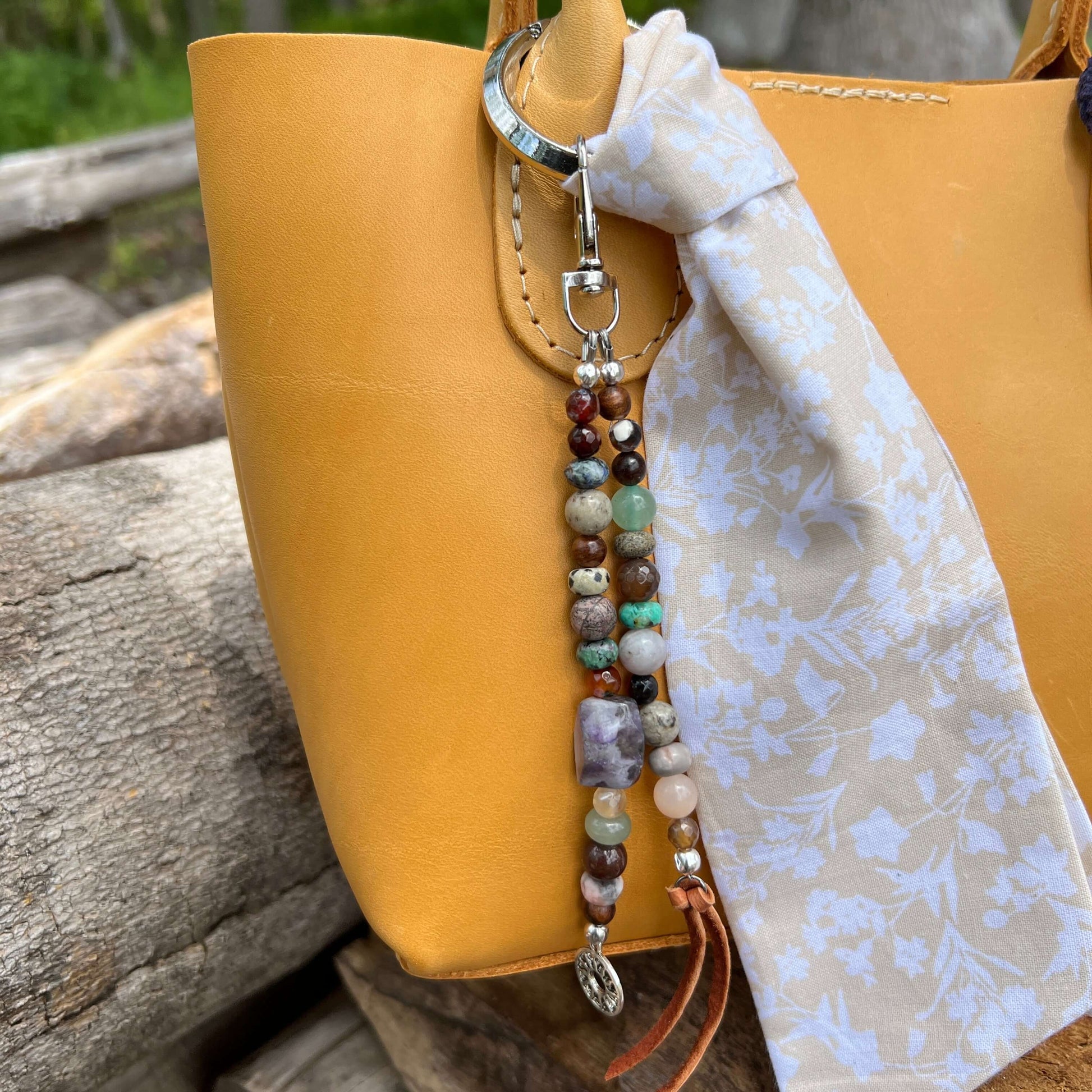 Boho Beaded Purse CharmGive your handbag or purse an instant boho cowgirl vibe with a beaded purse charm. Constructed on heavy gauge beading wire in natural stones with bohemian charms and leather tassel on the ends. Each charm is between 5-6" length from