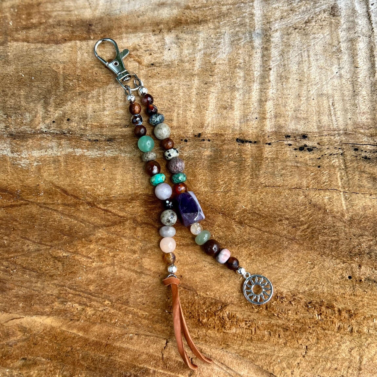 Boho Beaded Purse CharmGive your handbag or purse an instant boho cowgirl vibe with a beaded purse charm. Constructed on heavy gauge beading wire in natural stones with bohemian charms and leather tassel on the ends. Each charm is between 5-6" length from