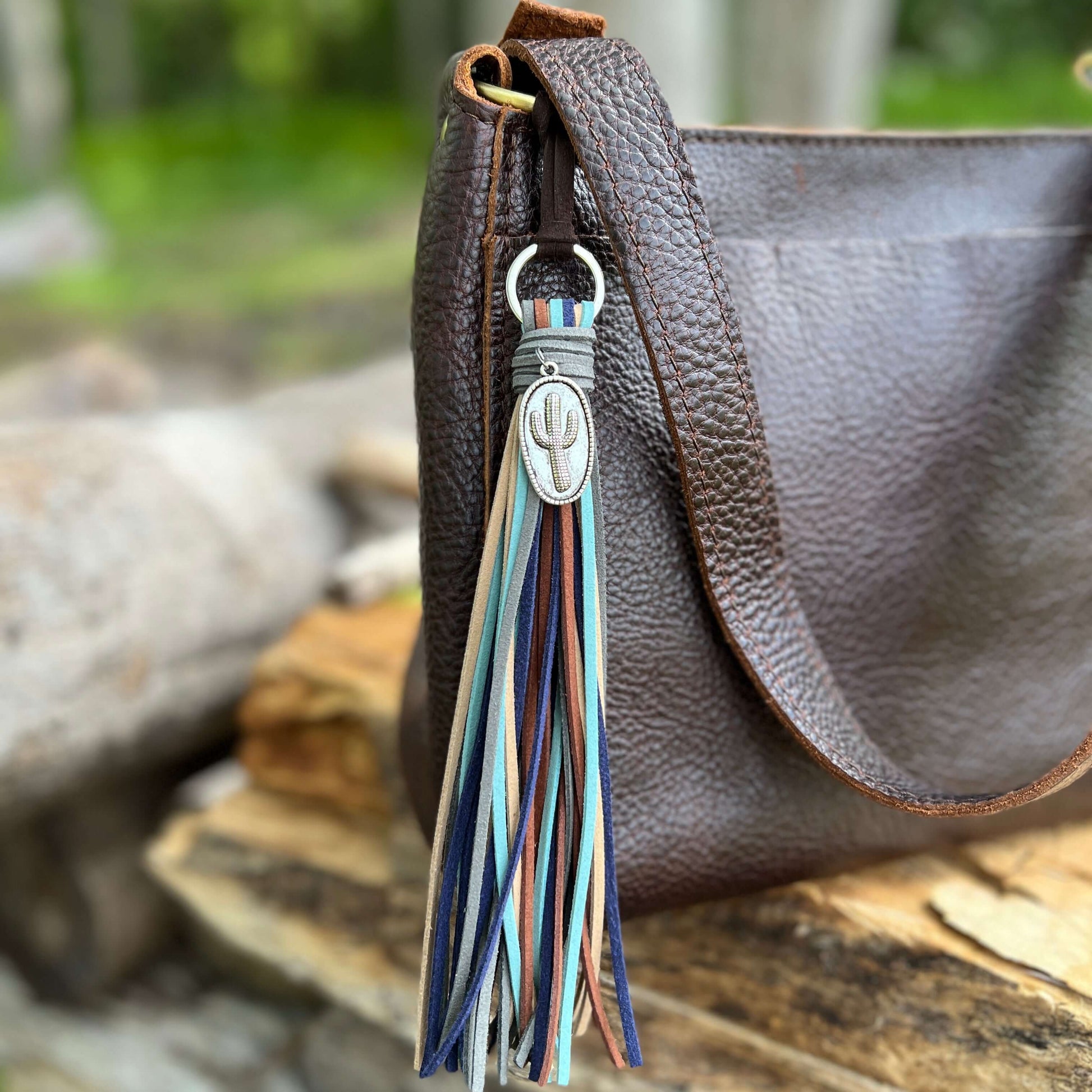 Tassel Purse Charm - Western Style with CactusChic and simple faux suede tassel purse charm with give your tote or bag an instant western vibe. Crafted with earthy colors of faux suede in navy, dusty blue, sand brown, cocoa brown and dark gray and accente