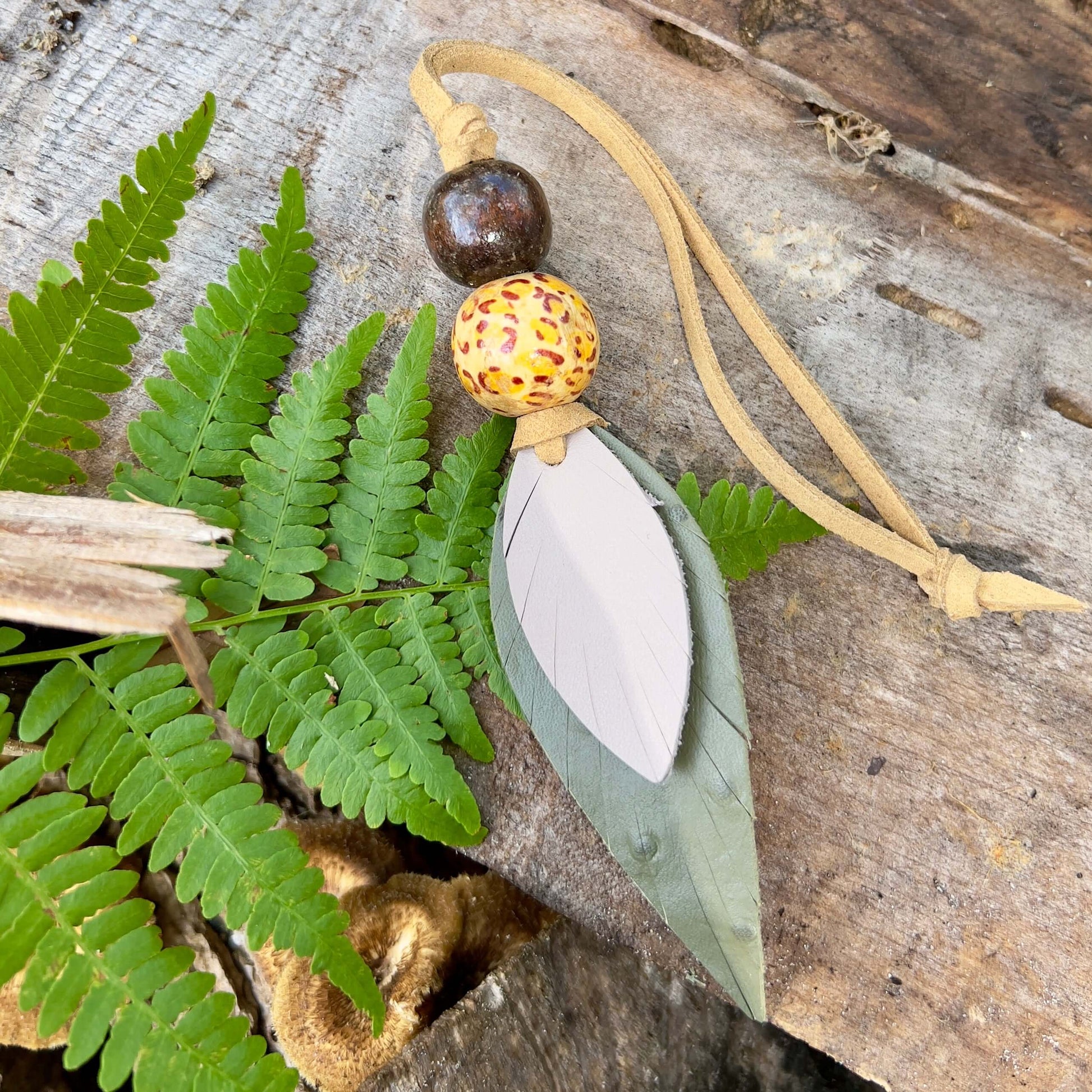 Leather Feather Boho Purse CharmGenuine leather feather purse charm with give your handbag or tote an instant update. Wooden beads give the charms a funky boho vibe. Layer with tassels or multiple feathers for a unique look. Feather & beads are 5" long Fa