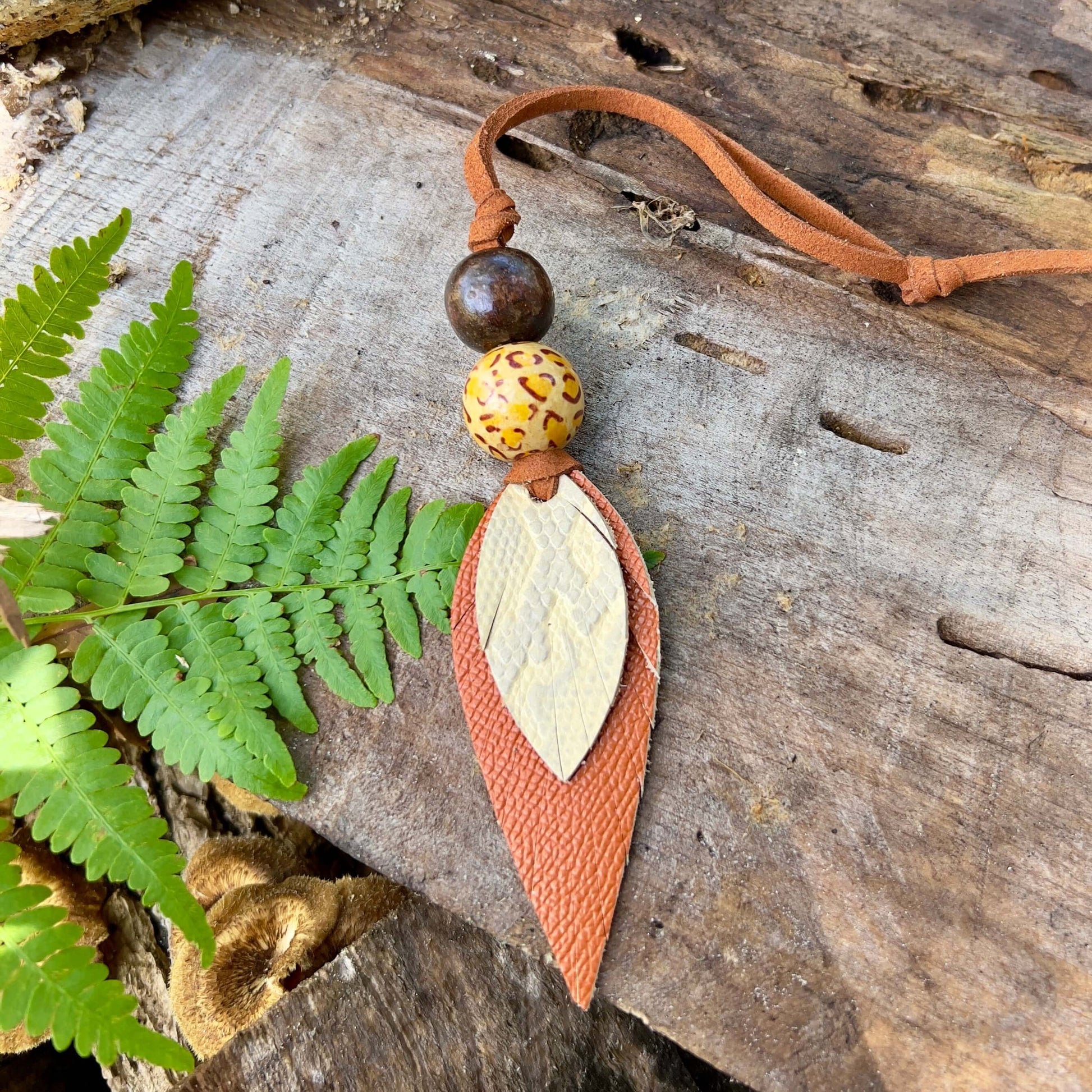 Leather Feather Boho Purse CharmGenuine leather feather purse charm with give your handbag or tote an instant update. Wooden beads give the charms a funky boho vibe. Layer with tassels or multiple feathers for a unique look. Feather & beads are 5" long Fa