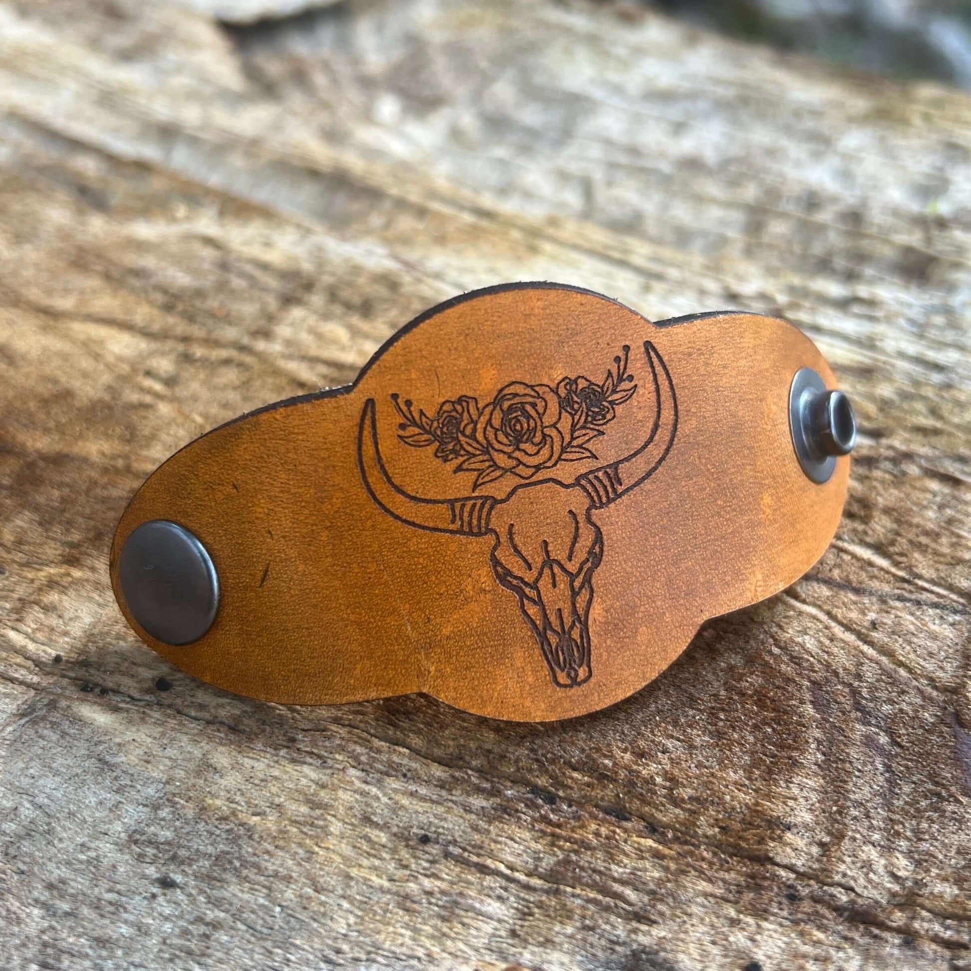 Bandana Slide - Vintage Tan Leather - Skull and RosesSimple and chic leather bandana slide. Classic style snaps on or slides over light weight scarves and bandanas. 3.75" long and 1.75" wide. Snaps at 3" Genuine veg tanned leather laser cut and engraved.