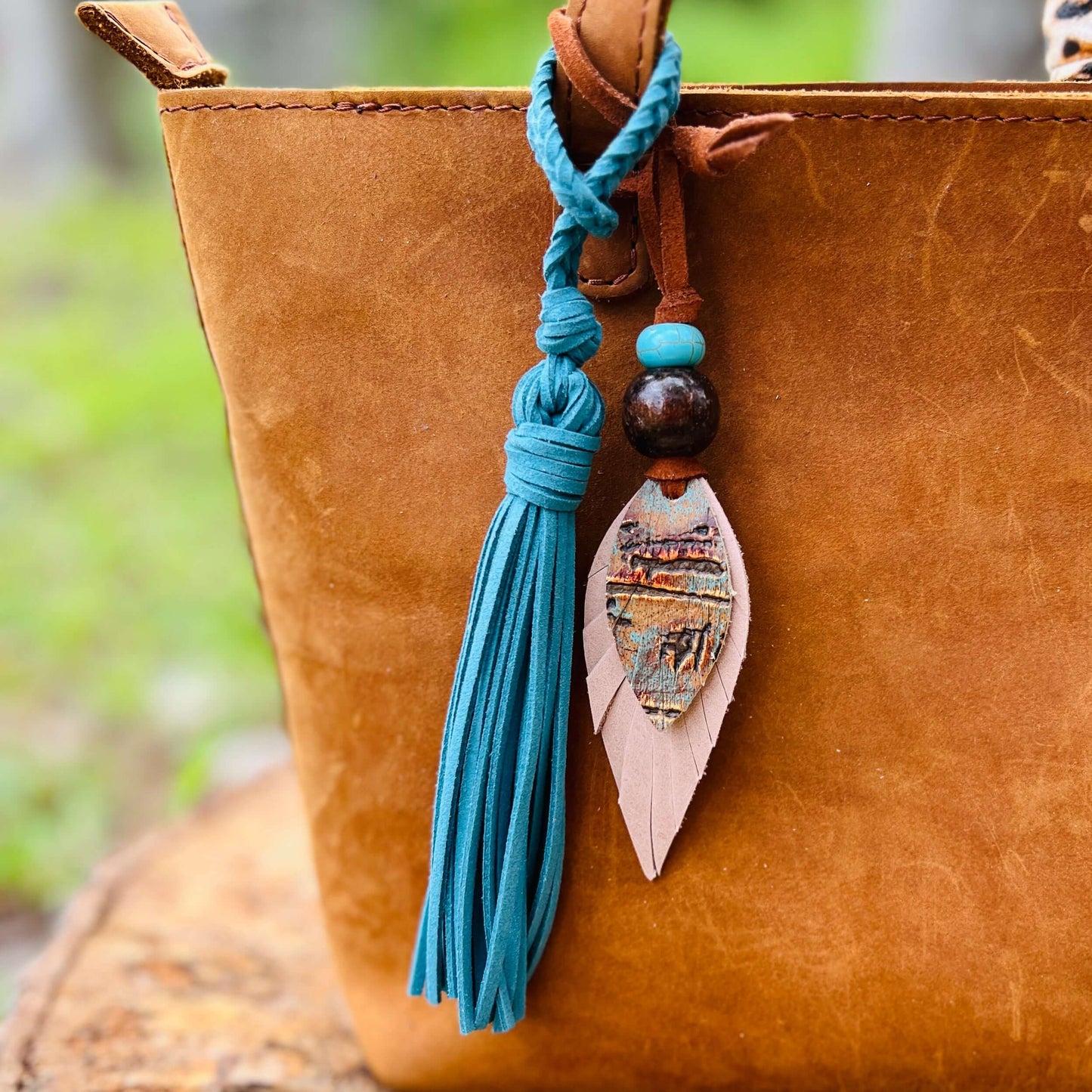 Leather Feather Boho Purse CharmGenuine leather feather purse charm with give your handbag or tote an instant update. Wooden beads give the charms a funky boho vibe. Layer with tassels or multiple feathers for a unique look. Feather & beads are 5" long Fa