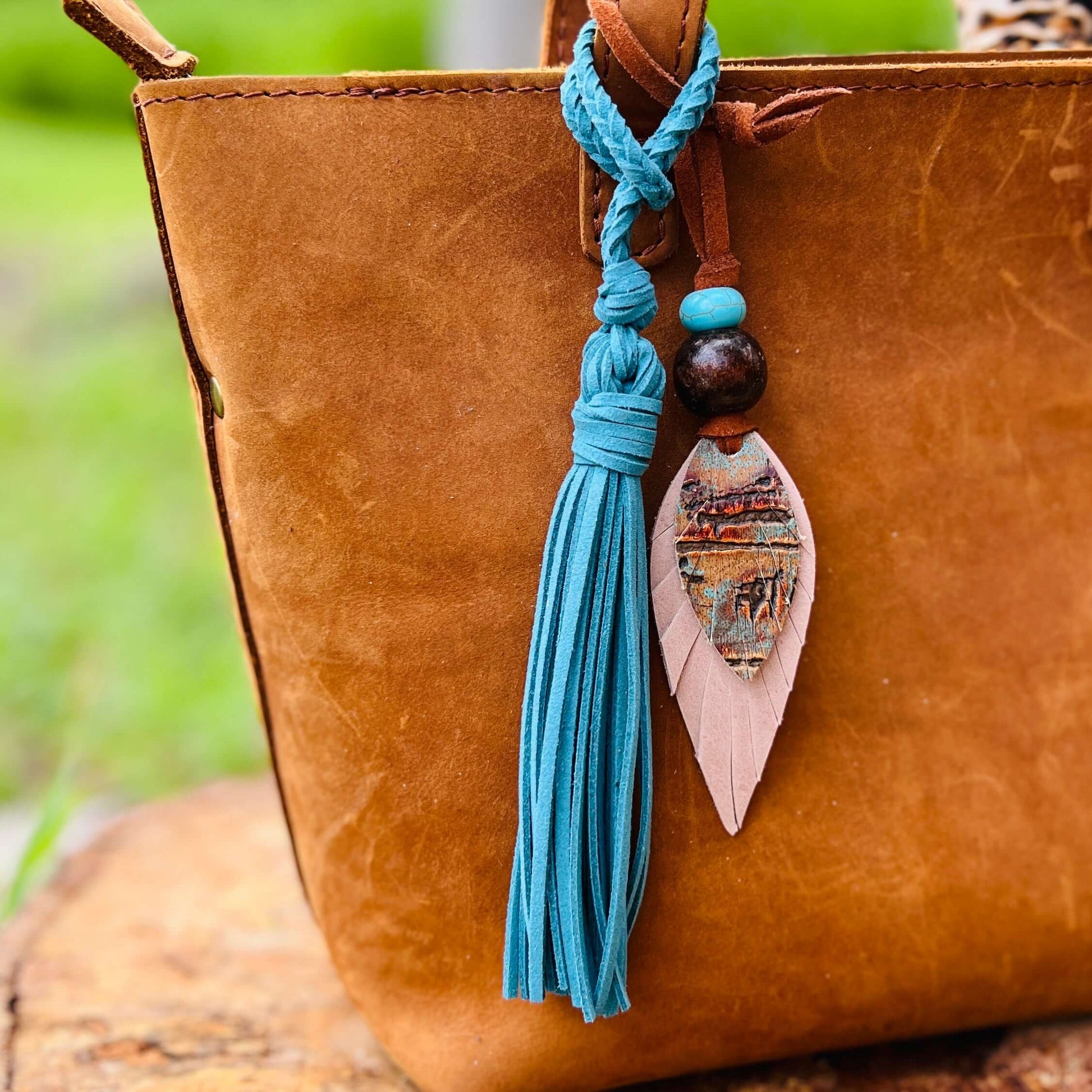 Leather Feather Boho Purse CharmGenuine leather feather purse charm with give your handbag or tote an instant update. Wooden beads give the charms a funky boho vibe. Layer with tassels or multiple feathers for a unique look. Feather & beads are 5" long Fa