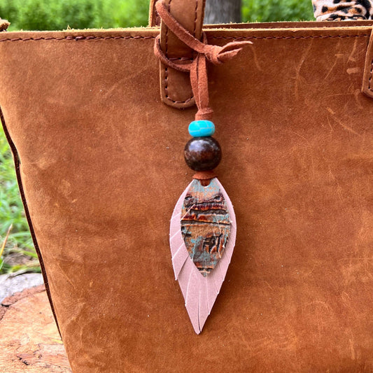 Leather Feather Boho Purse CharmGenuine leather feather purse charm with give your handbag or tote an instant update. Wooden beads give the charms a funky boho vibe. Layer with tassels or multiple feathers for a unique look. Feather & beads are 5" long Fa