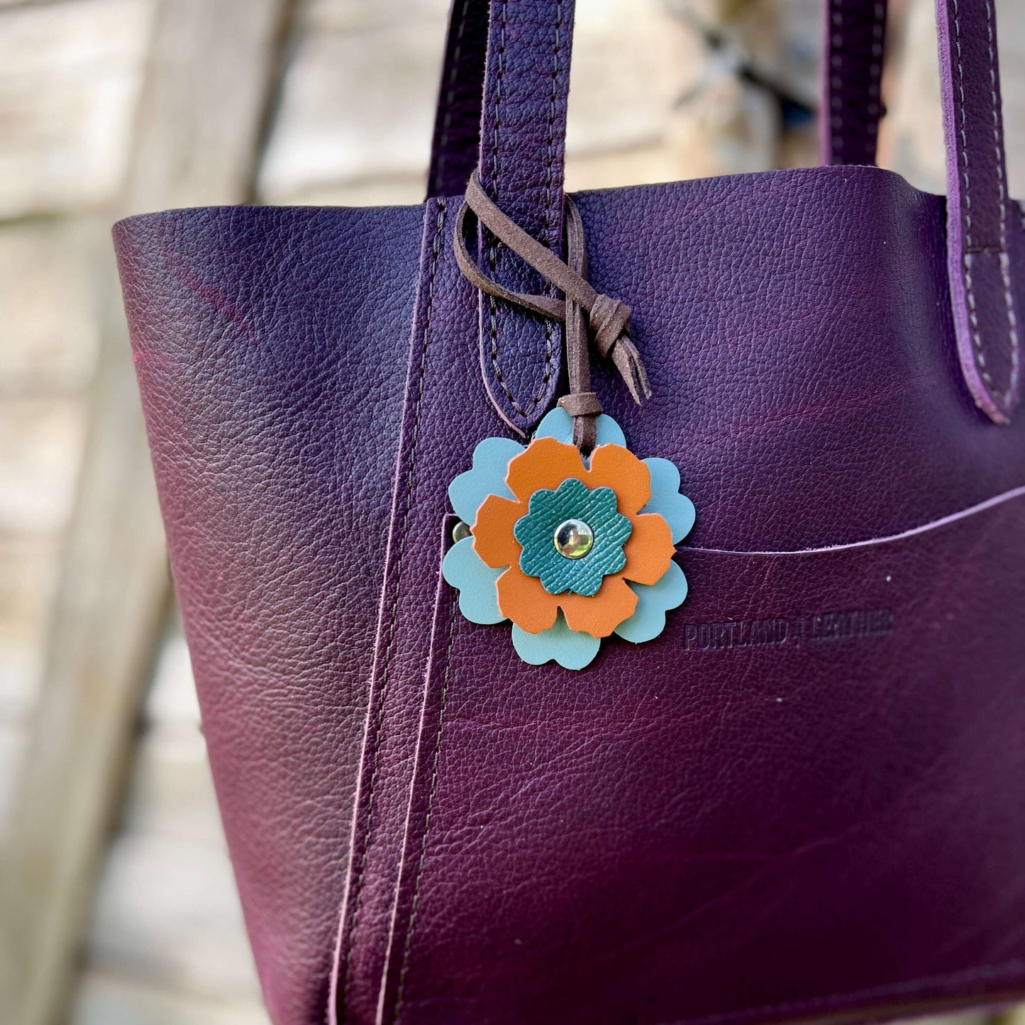 Small Leather Flower Purse Charm - Grey-Blue, Orange and TealWhen you want just a little pop of color for your handbag or purse. Update an old bag or tote with a genuine leather layered flower. Add a single flower to your small cross body or layer with ot