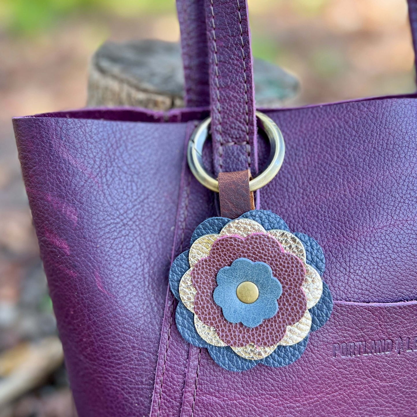 Leather Flower Bag Charm - Deep Blue, Gold, Plum WineLeather flower charms are the perfect way to add a little flair to your handbag, tote or purse. Handcrafted with layers of genuine leather and securely riveted to a leather loop with your choice of hard