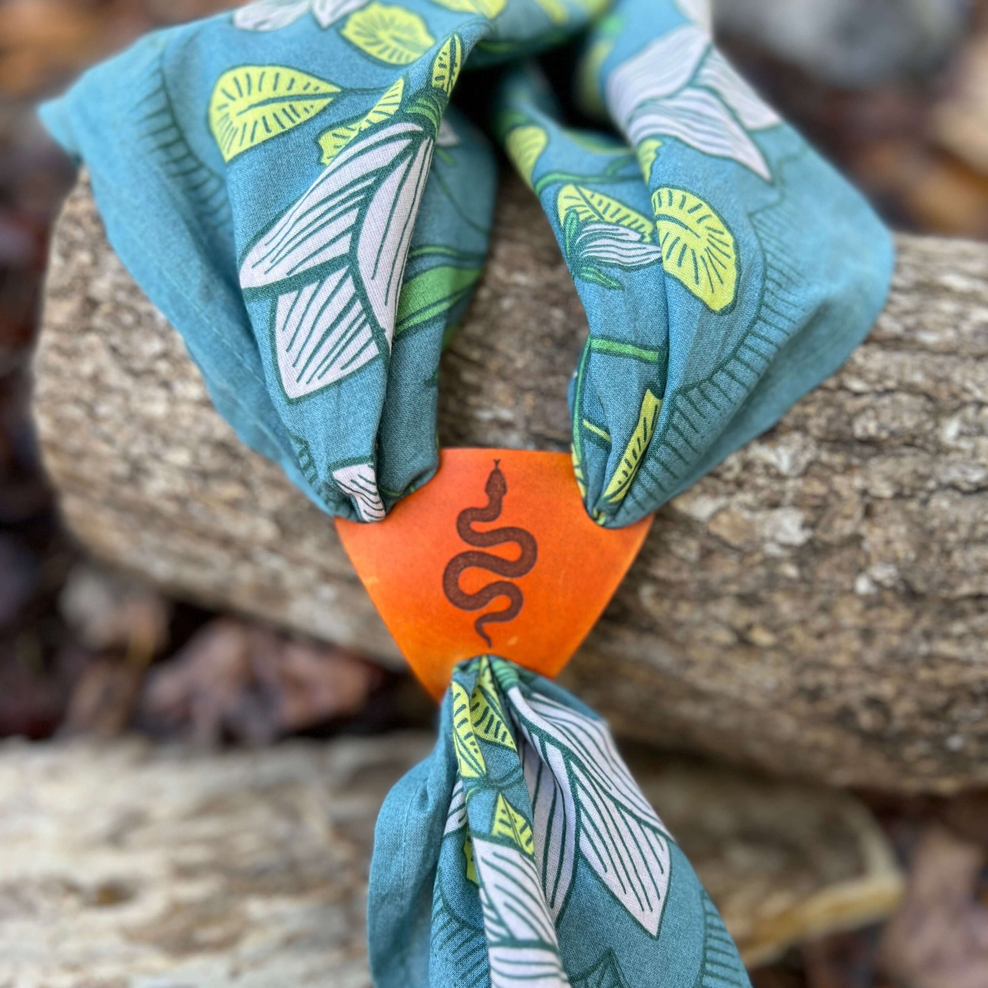 Bandana Slide Triangle - Antiqued Saddle Tan Leather - SnakeSimple and chic leather bandana slide. Triangle style slides over light weight scarves and bandanas. 2.75" long on each edge. 2.5" tall Genuine veg tanned leather laser cut and engraved. Dyed wit