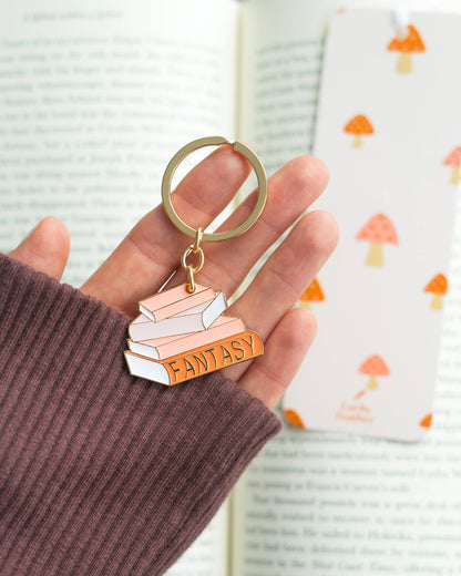 Keychain with 'Fantasy' book design held by a hand against a light background
