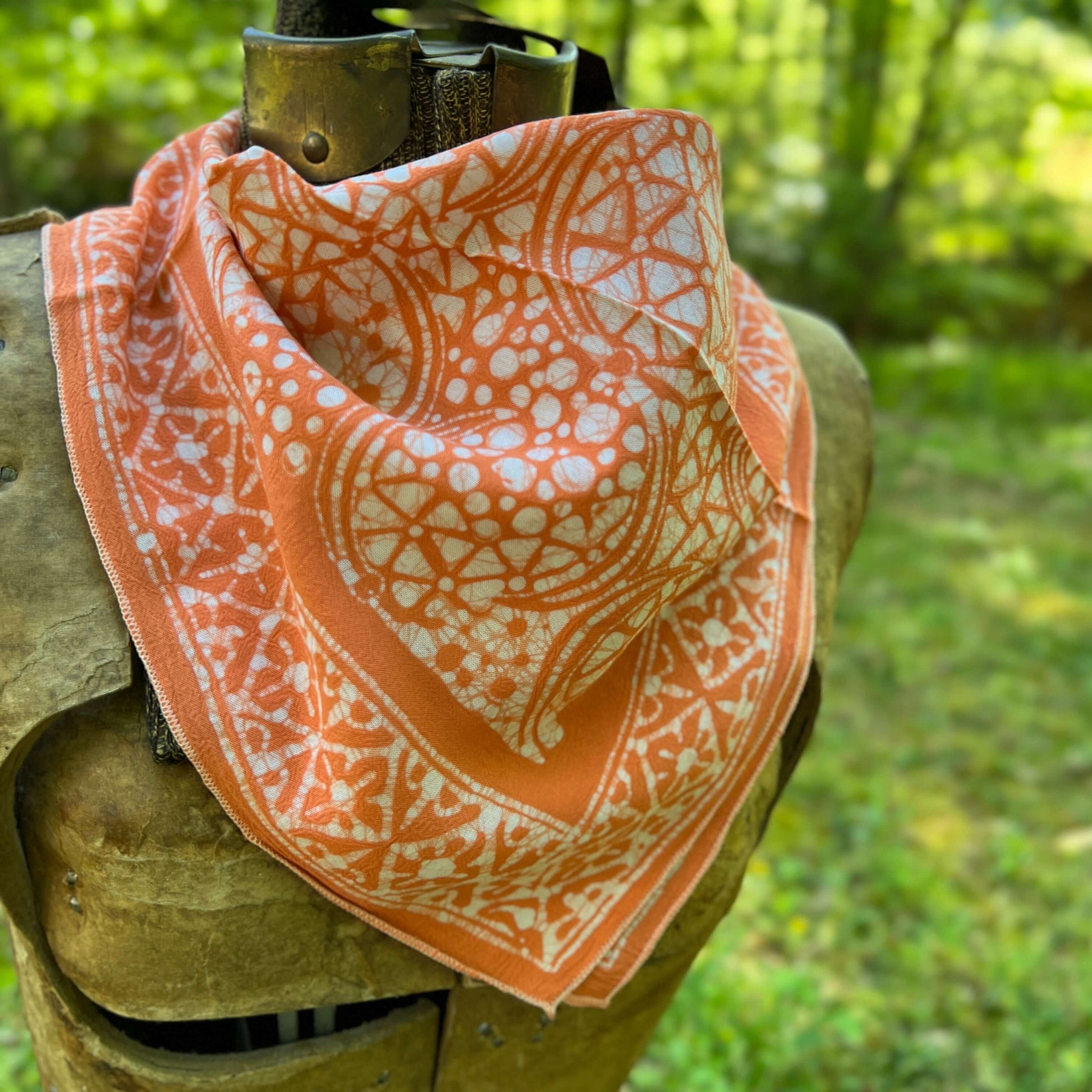Orange and white patterned bandana draped over a wooden object with a natural background