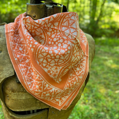 Orange and white patterned bandana draped over a wooden object with a natural background