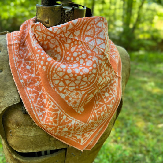 Orange and white patterned bandana draped over a wooden object with a natural background