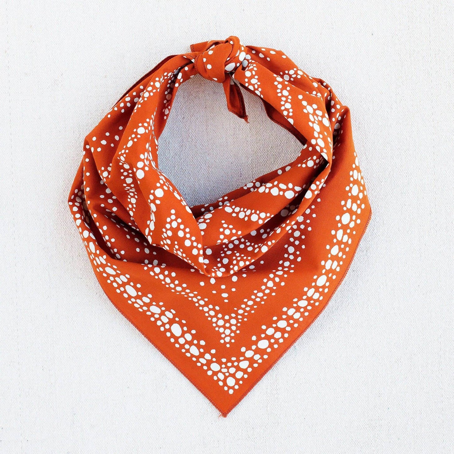 Orange bandana with white pattern on a light gray background
