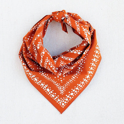 Orange bandana with white pattern on a light gray background