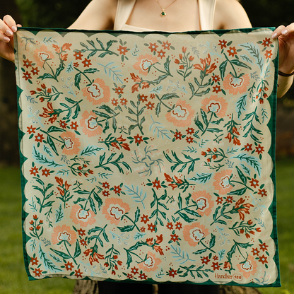Person holding a floral patterned fabric with green, orange, and white colors.