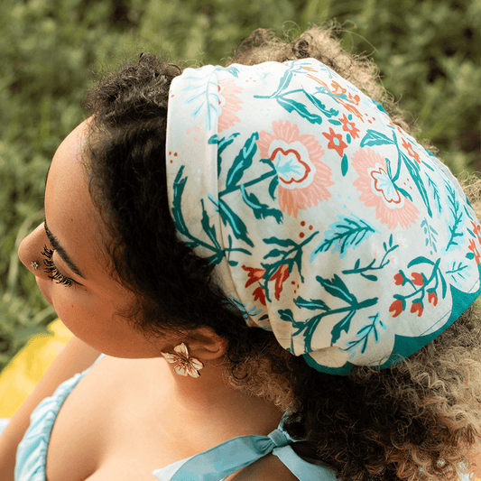 Person wearing a floral headscarf with a blurred green background