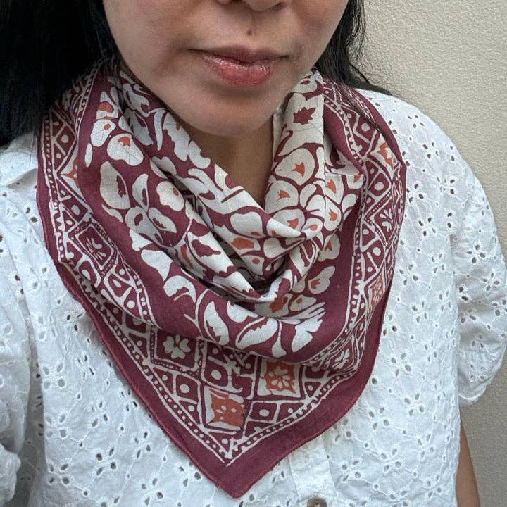 Person wearing a patterned scarf with a neutral background