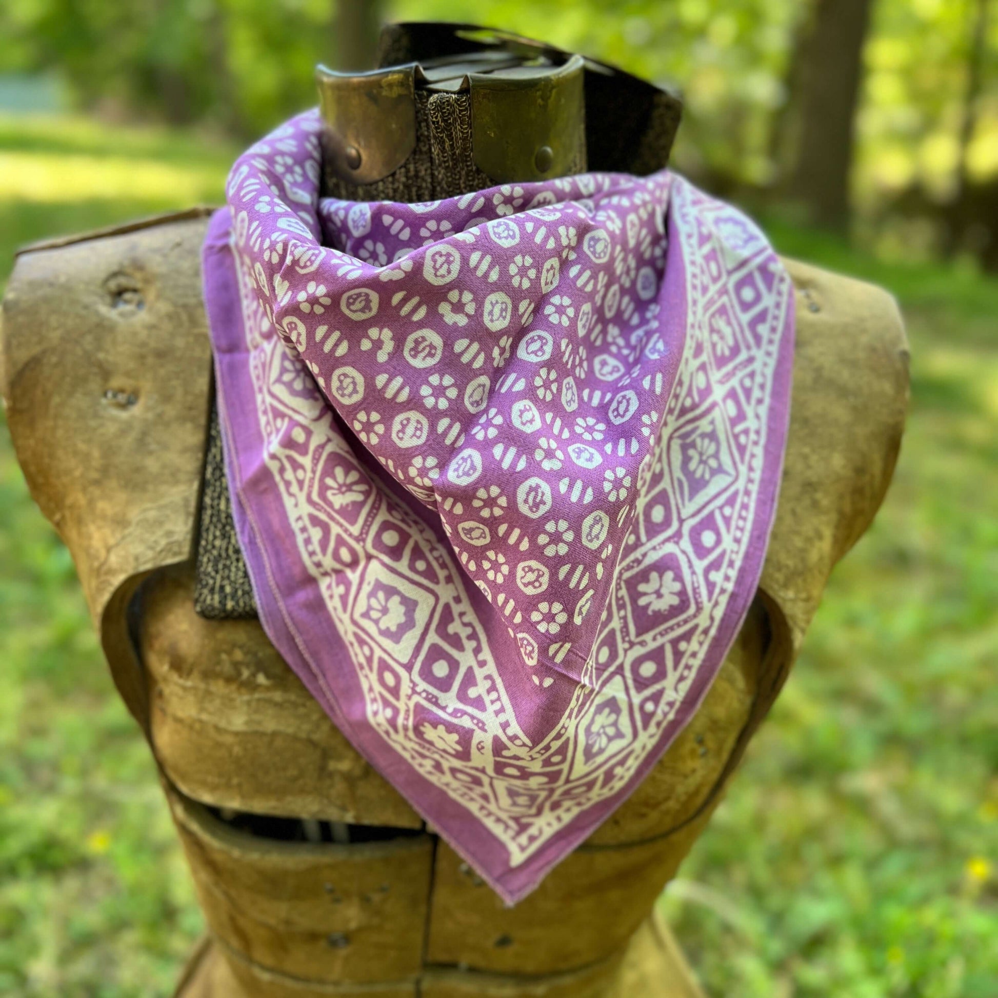 Purple patterned bandana on a wooden mannequin with a natural outdoor background