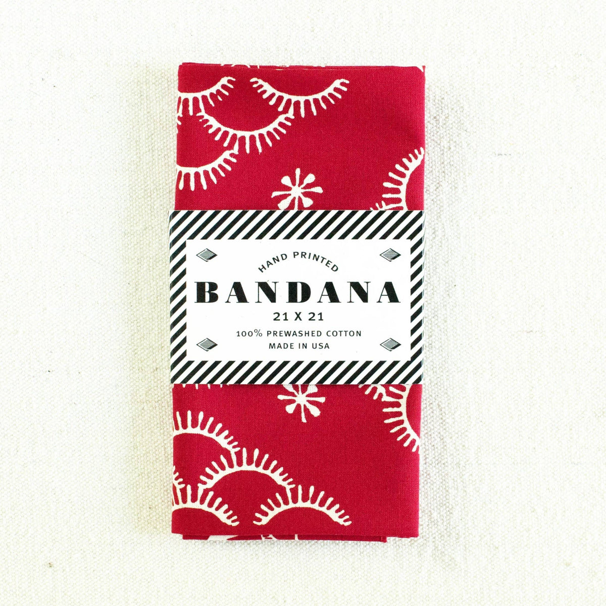 Red bandana with white patterns and packaging on a white background