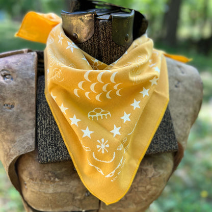 Yellow bandana with white patterns against a blurred natural background