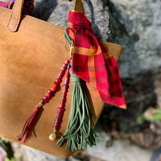 Decorative keychain with beads and tassel attached to a brown leather bag.