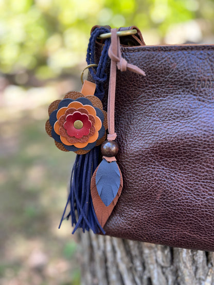 blue and brown leather feather bag charm with flower and navy tassel on brown bag