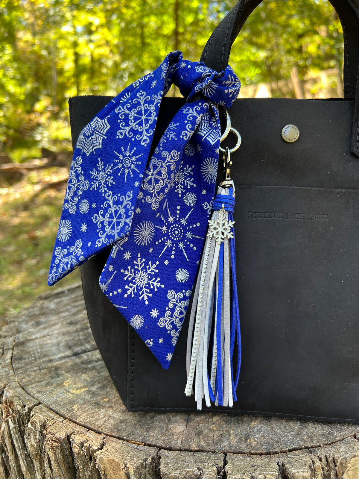 blue and silver tassel bag charm with snowflake shown with blue scarf on black bag