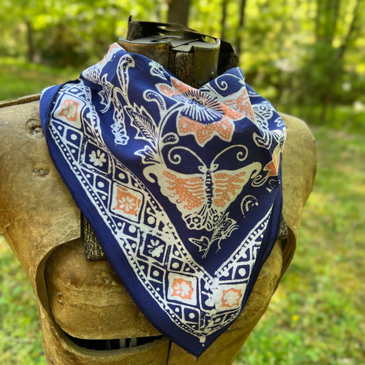 Blue bandana with a white and orange pattern on a wooden block against a natural background