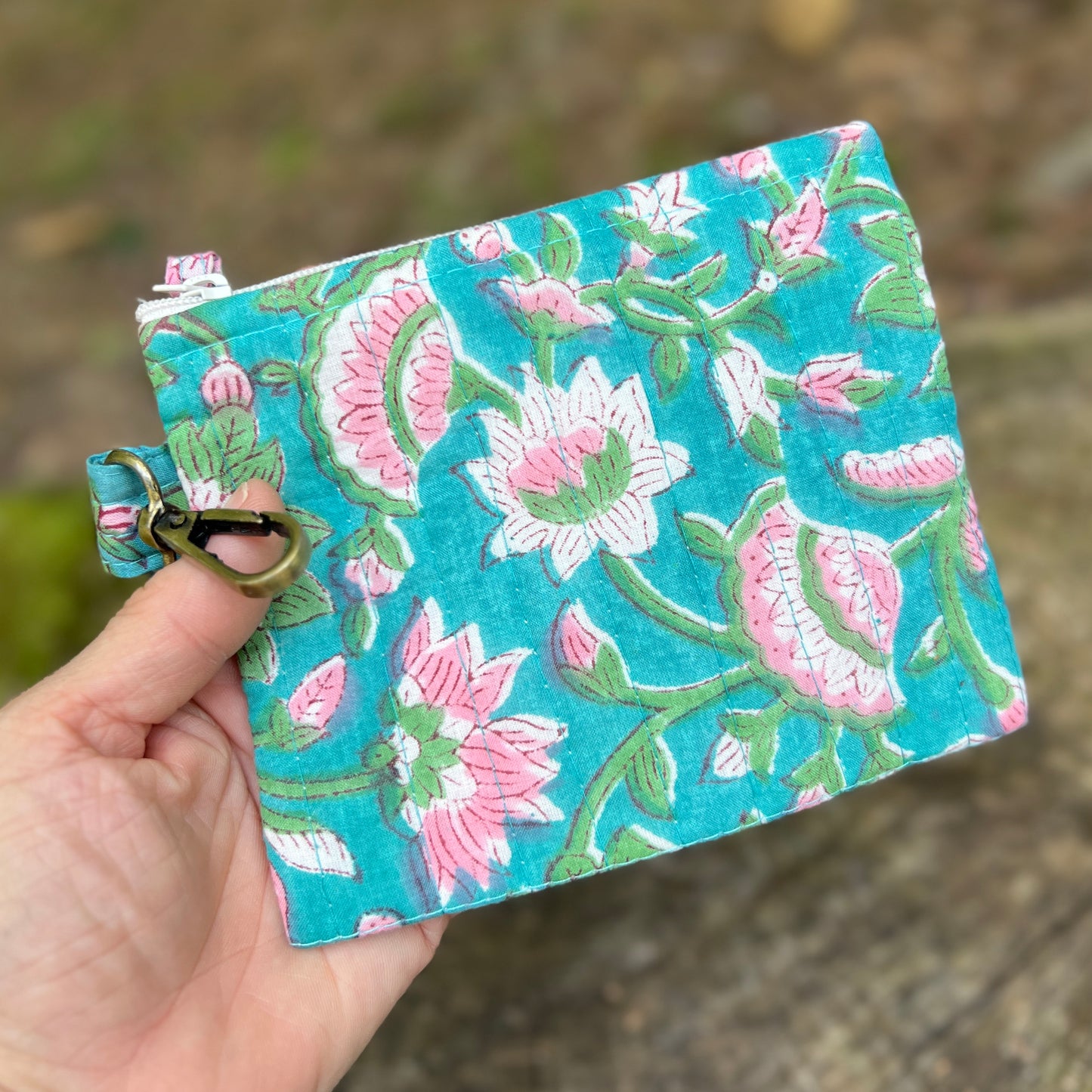 Floral embroidered pouch held by a hand with a natural background