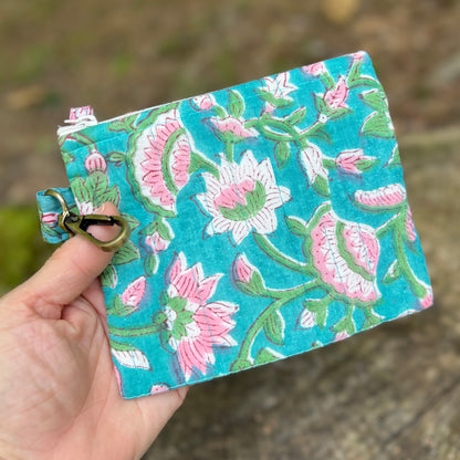 Floral embroidered pouch held by a hand with a natural background