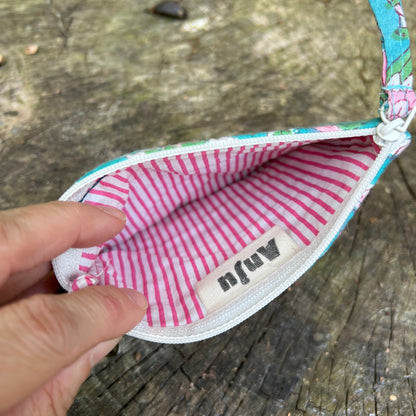 Small fabric pouch with pink and white striped interior on a wooden surface