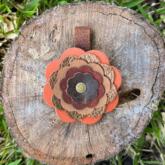 Decorative flower made of leather on a wooden log with grass in the background